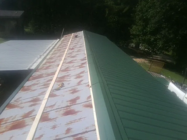 Old rusted panels beside newly installed green metal roofing — Wind Damage Roof Repair by Roofing Brothers in New Kent