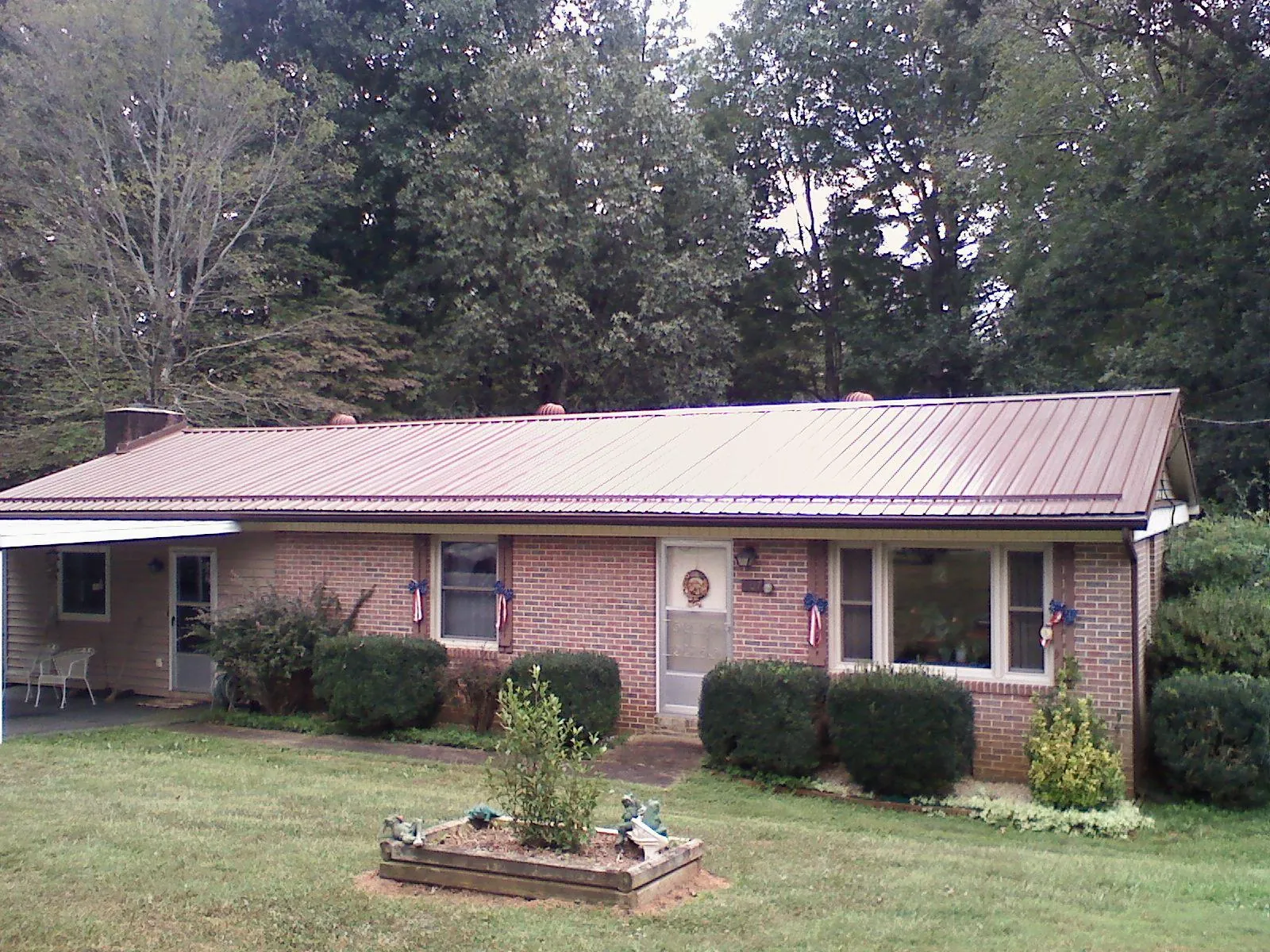 Bronze metal roof on a brick ranch home with a carport in New Kent