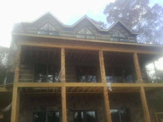 Dormers and porch framing on a large log home under construction — Roof Coating work by our crew in New Kent