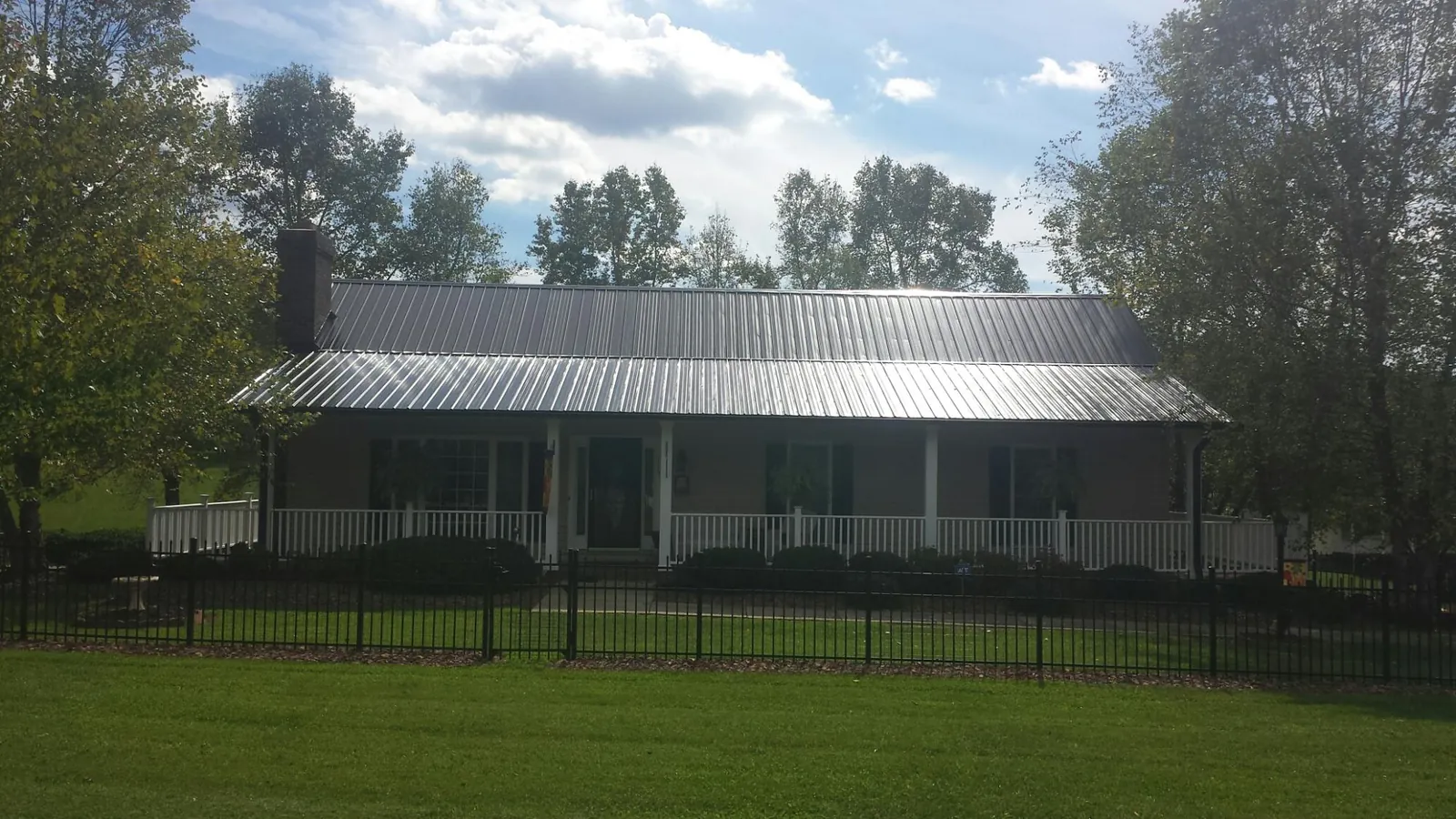 Gray metal roof on a brick ranch with a full width front porch — Gutter Guard Installation work by our crew in New Kent