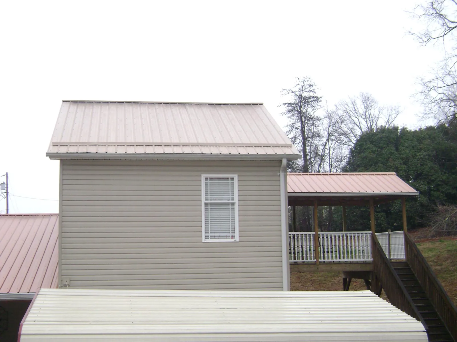Tan metal roofs on a two story addition and attached porch, from a Roof Replacement job in New Kent