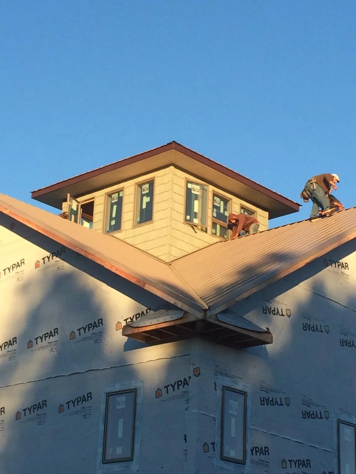 Roofers working around a rooftop cupola on a new metal roof at sunset — Roof Waterproofing in New Kent by Roofing Brothers